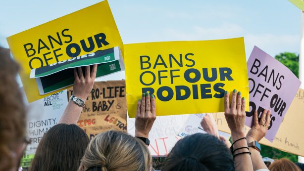 Yellow protest placards that say, "BANS OFF OUR BODIES"